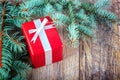 Close-up red present box on a wooden and pine branch background. Christmas celebration concept.