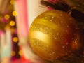 Close-up the decorative single golden Christmas ball with de-focused bokeh lights.