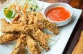 Close up deep fried chicken wings with vegetable side dish and chili sauce, served on the white dish on wood table. Royalty Free Stock Photo