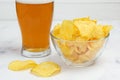 Close-up of a deep glass bowl with potato chips and a glass of light beer Royalty Free Stock Photo