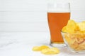 Close-up of a deep glass bowl with potato chips and a glass of light beer Royalty Free Stock Photo