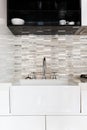 Close up of a deep white kitchen sink and tiled splashback Royalty Free Stock Photo