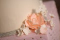 Close up of delicate icing floral decoration on a tiered cake, embellished with velvet pastel pink icing and sugar flowers