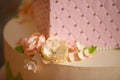 Icing floral decoration on a tiered cake, embellished with velvet pastel pink icing, sugar flowers and silver edible pearls