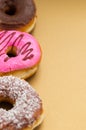 Close up of a delicious assorted donuts with pink, chocolate, coconut, peanut glazed accommodated in one line over a