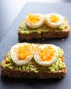 Close-up of delicious avocado toast topped with sliced boiled eggs and sesame seeds