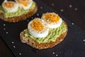 Close-up of delicious avocado toast topped with sliced boiled eggs and sesame seeds