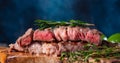 Close-up of delicious beef steak on a wooden table, still life. Rare steak. Dark blue background, cooking and recipe book, cooking