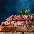 Close-up of delicious beef steak on a wooden table, still life. Rare steak. Dark blue background, cooking and recipe book, cooking