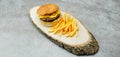 Delicious tasty hamburger with beef cutlet, french fries, fresh vegetables and  2 slices of cheddar cheese on vintage woode Royalty Free Stock Photo