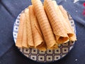 Close-up of delicious chocolate waffle rolls lie on white plate. Preparation of a sweet dessert. White clean kitchen and table. Royalty Free Stock Photo