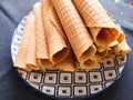 Close-up of delicious chocolate waffle rolls lie on white plate. Preparation of a sweet dessert. White clean kitchen and table. Royalty Free Stock Photo