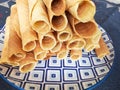 Close-up of delicious chocolate waffle rolls lie on white plate. Preparation of a sweet dessert. White clean kitchen and table. Royalty Free Stock Photo