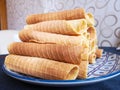 Close-up of delicious chocolate waffle rolls lie on white plate. Preparation of a sweet dessert. White clean kitchen and table. Royalty Free Stock Photo