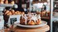Close-up of a delicious cinnamon roll with icing, displayed on a white plate in a bakery setting Royalty Free Stock Photo