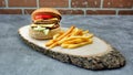 Delicious double tasty hamburger with beef cutlet, french fries, fresh vegetables and  2 slices of cheddar cheese on vintage woode Royalty Free Stock Photo