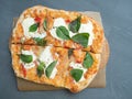 Close-up of delicious fresh crispy Roman pizza with cheese and herbs on a gray background. Craft paper, linen napkin. Top view,