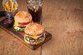 Close-up of delicious fresh home made burger with lettuce, cheese, onion and tomato on a rustic wooden board. Also fries and Cola Royalty Free Stock Photo