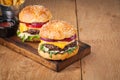 Close-up of delicious fresh home made burger with lettuce, cheese, onion and tomato on a rustic wooden board. Also fries with ketc Royalty Free Stock Photo