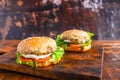 Close-up of delicious fresh home made burger with lettuce, cheese, onion and tomato on a rustic wooden plank on wooden table Royalty Free Stock Photo