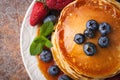Close-up delicious pancakes, with fresh blueberries, strawberries and maple syrup on a rusty background. With copy space. Top view Royalty Free Stock Photo