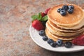 Close-up delicious pancakes, with fresh blueberries, strawberries and maple syrup on a rusty background. With copy space Royalty Free Stock Photo