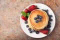 Close-up delicious pancakes, with fresh blueberries, strawberries and maple syrup on a rusty background. With copy space Royalty Free Stock Photo
