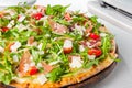 Close up Delicious Pizza with hamon and cherry tomato slices, parmezan cheese and arugula on the wooden board on t Royalty Free Stock Photo