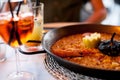 Close-up of delicious seafood valencia paella with king prawns, rice with spices in pan and Glass of aperol spritz cocktail long d Royalty Free Stock Photo