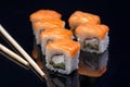 sushi rolls with chopsticks on a black glossy Board.