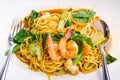 Close up delicious yellow fried noodles with soy sauce, prawns, vegetables and mushrooms on the white plate background. Thai stir-