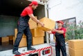 Close up of delivery man stand on truck and send parcel or box to his co-worker during transport the product to customer house Royalty Free Stock Photo