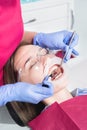 Close-up of a dentist applying polymer from a syringe to the inside of a young patient`s front tooth in a dental office