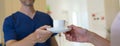 Close-up of dentist giving cup of coffee to patient, private dental clinic.