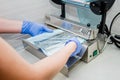 Close up dentist`s assistant hands in gloves packing dental instrument set for autoclaving in a plastic bag using vacuum packing