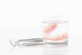 Close up of dentures in glass of water and dental tool with notice paper on white background Royalty Free Stock Photo