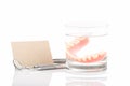Close up of dentures in glass of water and dental tool with notice paper on white background