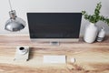 Close up of designer office interior with various objects, coffee cup and empty mock up place on computer monitor. Wooden desktop