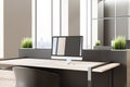 Close up of desk with empty laptop with reflections in modern office interior with window and city view. Royalty Free Stock Photo