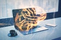 Close up of desktop with laptop, coffee cup and glowing digital polygonal mesh brain hologram on blurry background. The concept of