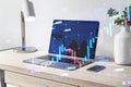 Close up of desktop workplace with laptop, other items and abstract growing forex chart on blurry background. Economy, up, growth