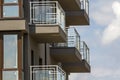 Close-up detail of apartment building wall with balconies and shiny windows on blue sky background. Royalty Free Stock Photo