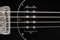 Close up detail of a black bass guitar pickups, frets and bridge