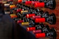 Close-up detail of black red wine bottles with red labels aligned and stacked horizontally on wooden shelves and bottle racks in a Royalty Free Stock Photo
