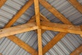 Close-up detail bottom view from inside of bright yellow wooden timber frame and gray metal tiling of alcove roof . Building, cons