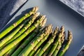 Close-up detail bunch of fresh raw green asparagus plant harvested at season on blue cerami plate kitchen background