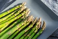 Close-up detail bunch of fresh raw green asparagus plant harvested at season on blue cerami plate kitchen background