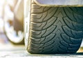 Close-up detail of car wheel with aluminum disc and black rubber tire protector on light blurred outdoors background. Durability,