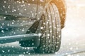 Close up detail car wheel with new black rubber tire protector on winter snow covered road. Transportation and safety concept Royalty Free Stock Photo