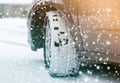 Close up detail car wheel with new black rubber tire protector on winter snow covered road. Transportation and safety concept